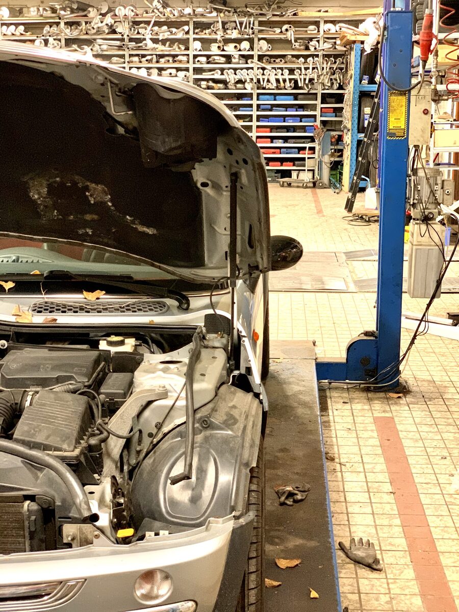 De werkplaats van TCE Autoservice met een auto op de brug
